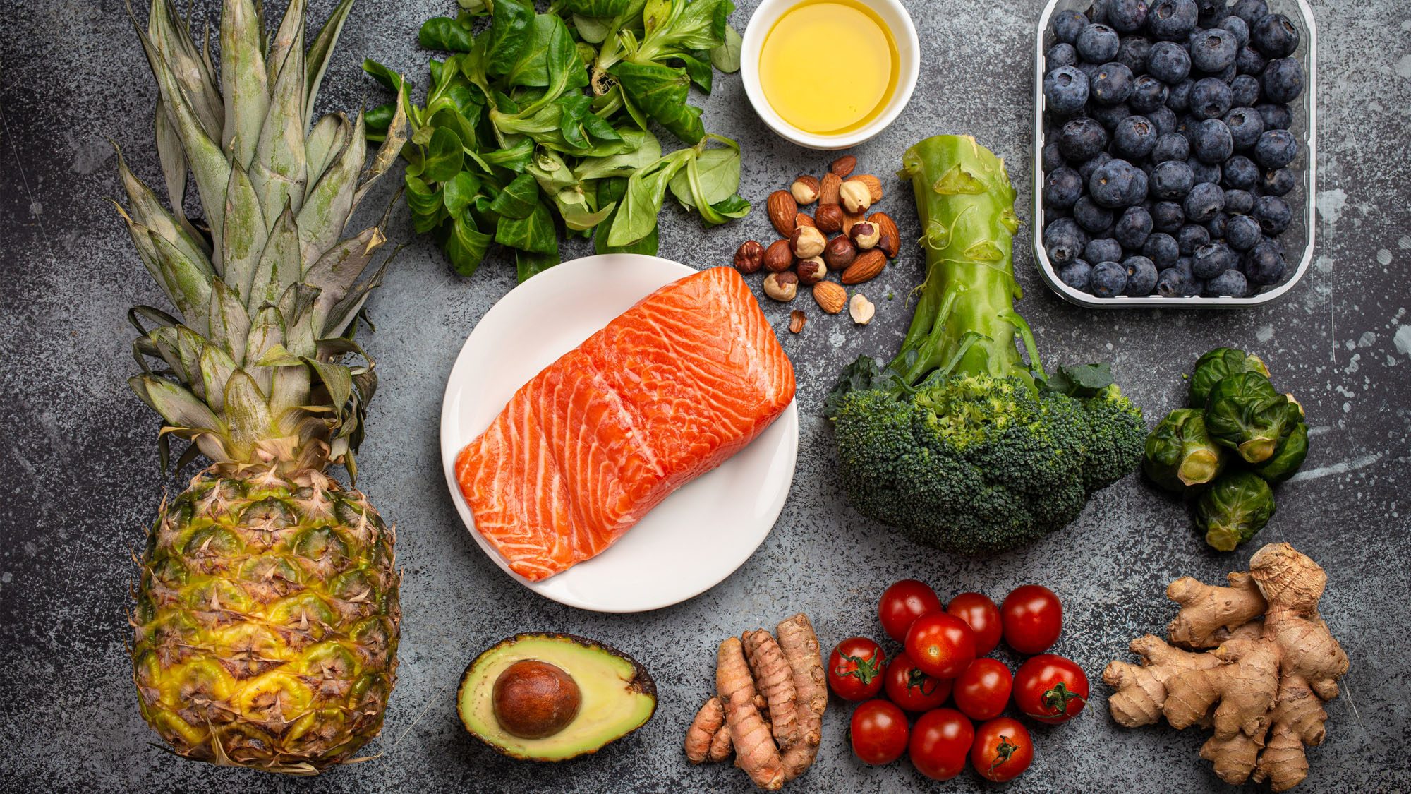 Assorted superfoods including salmon, almonds, and blueberries on a textured surface