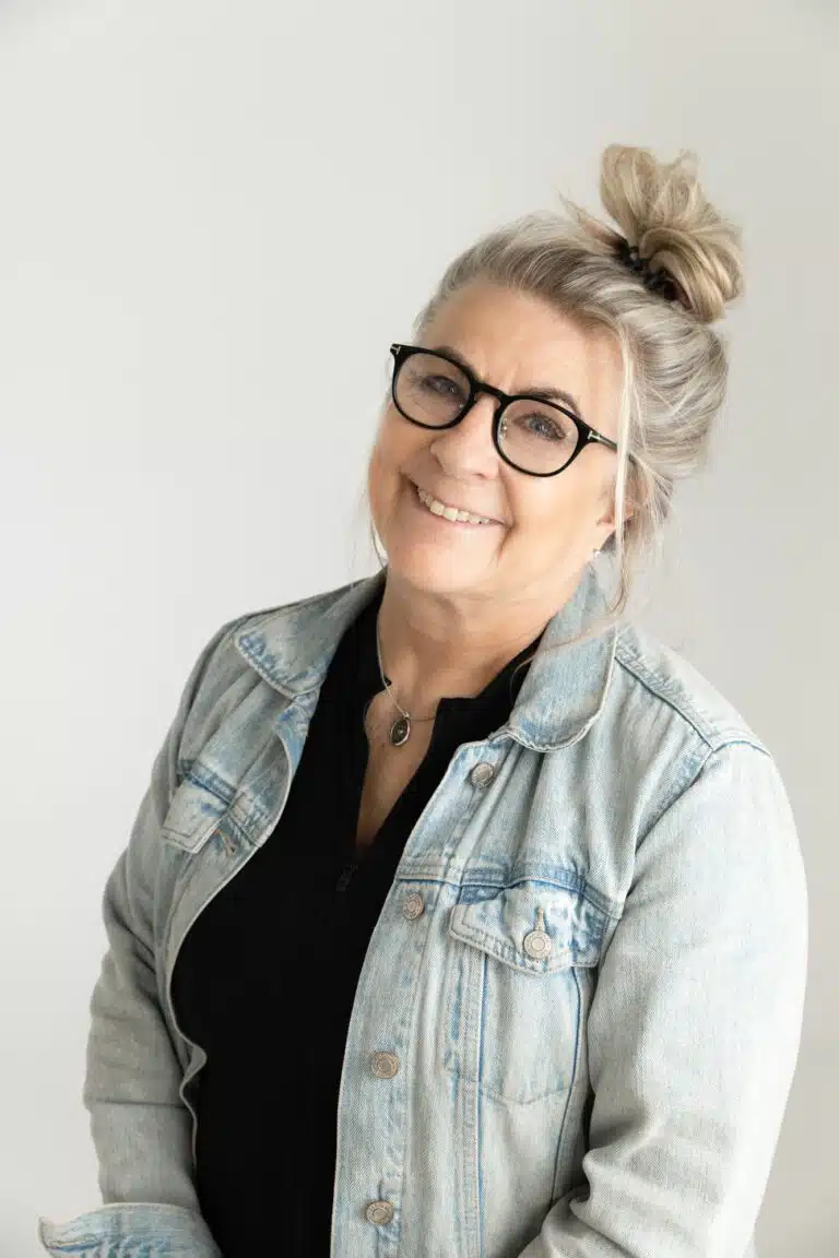 Smiling woman with glasses and bun in denim jacket