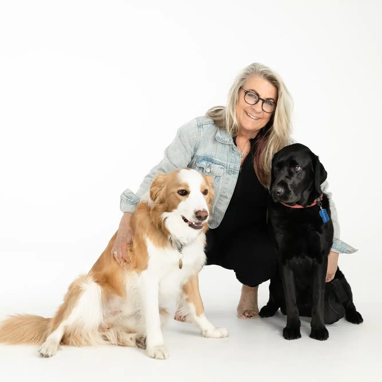 Smiling woman with glasses posing with two friendly dogs
