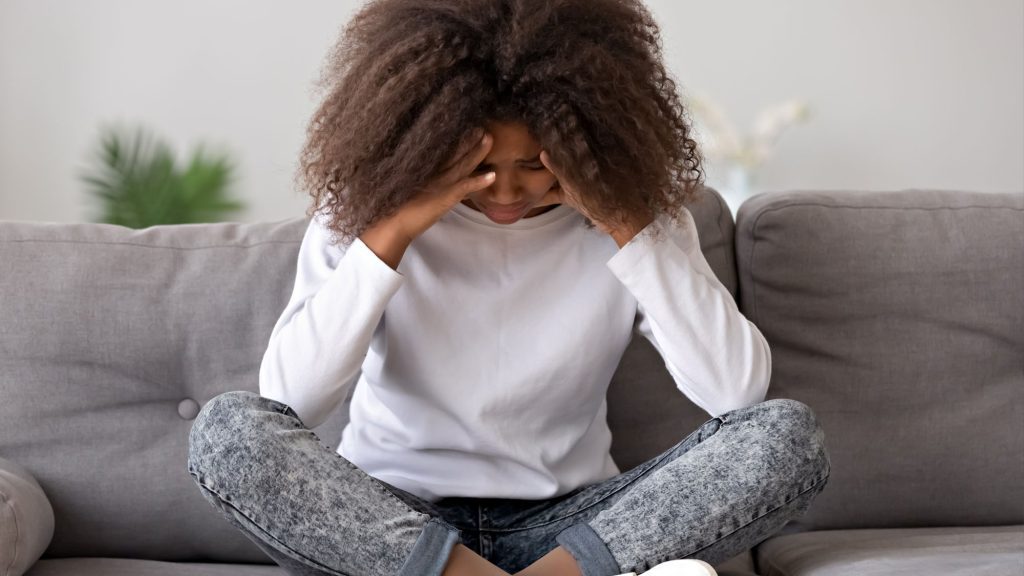 Woman with curly hair stressed on a couch