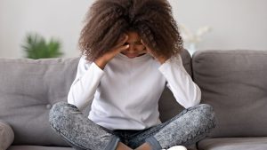Woman with curly hair stressed on a couch