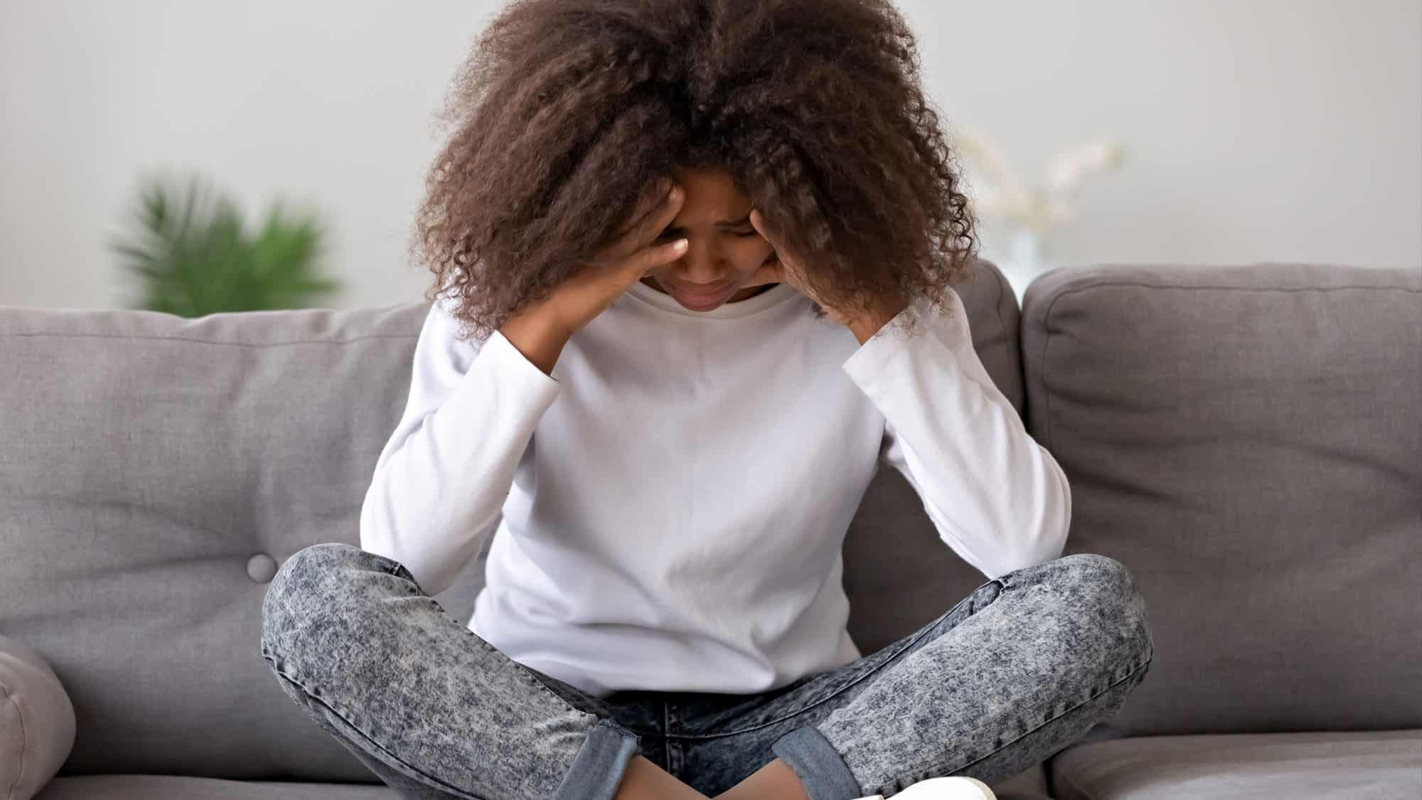 Woman with curly hair stressed on a couch