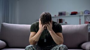 Man in distress sitting on a couch in a dimly lit room