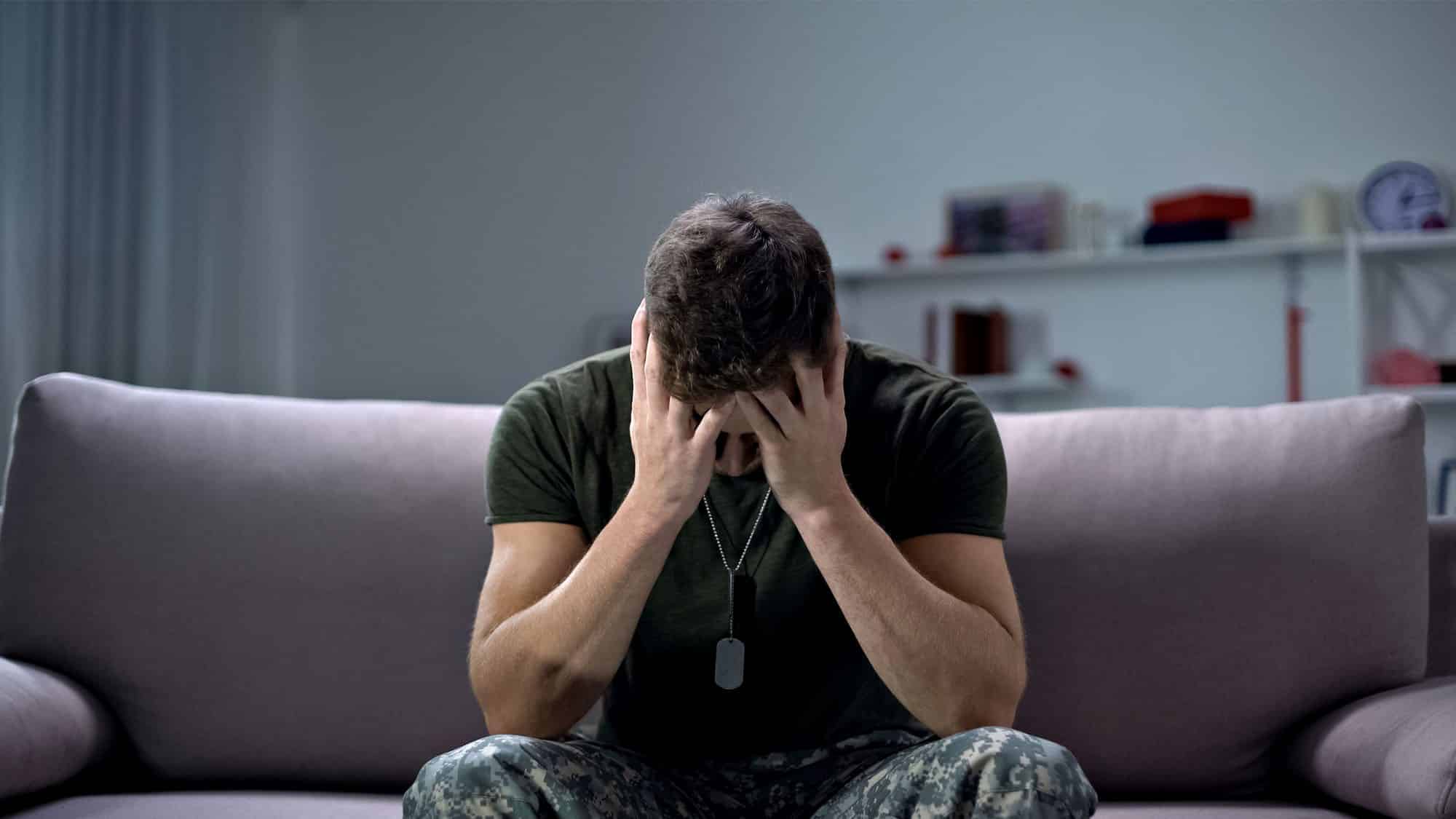 Man in distress sitting on a couch in a dimly lit room
