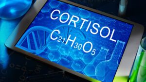 Tablet displaying cortisol chemical formula with DNA helix and lab tools