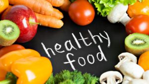 Assorted fresh fruits and vegetables encircling 'healthy food' text