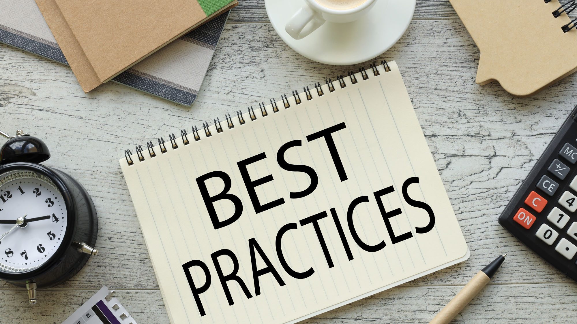 Notebook with 'Best Practices' on desk with office supplies