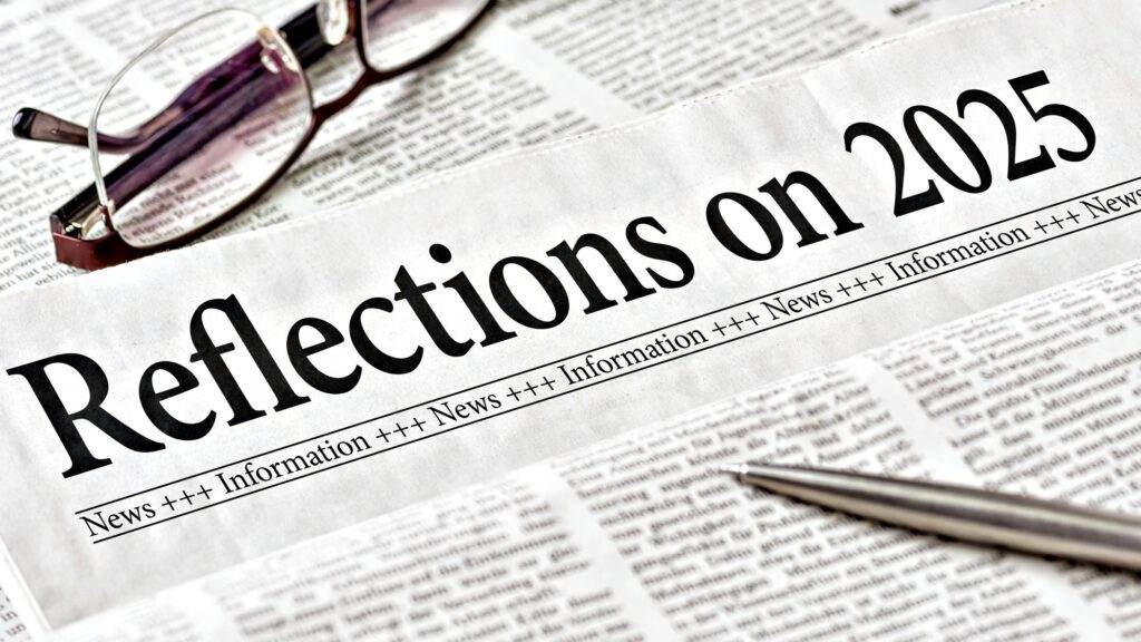 Newspaper headlined 'Reflections on 2025' with glasses and pen on newsprint