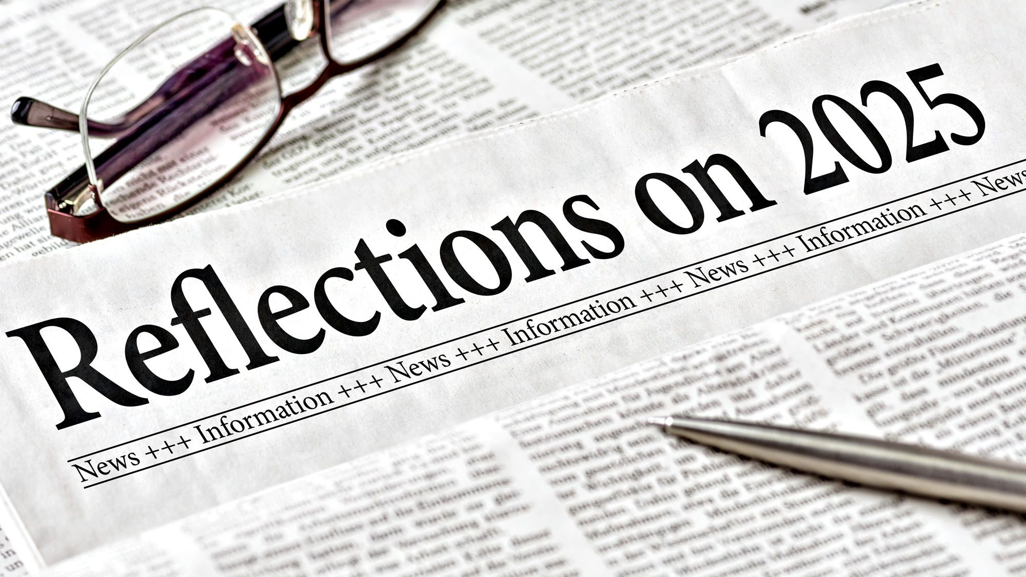 Newspaper headlined 'Reflections on 2025' with glasses and pen on newsprint