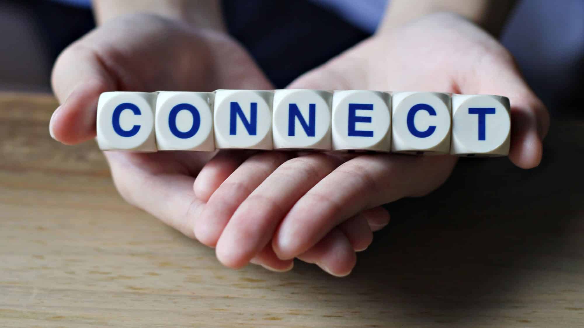 Hands holding letter blocks spelling 'CONNECT'