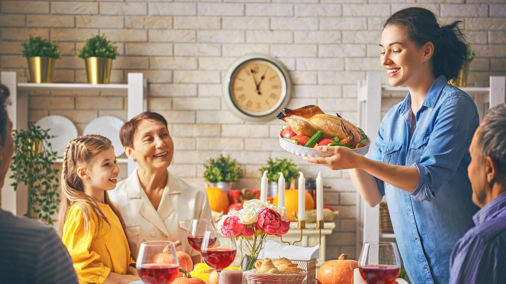 Family enjoying Thanksgiving dinner with turkey and wine