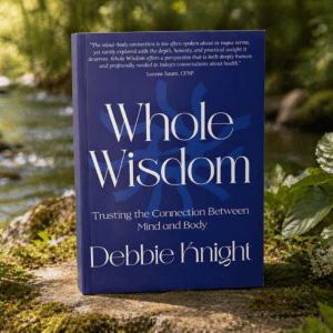 Whole Wisdom book by Debbie Knight on mind-body connection beside a stream