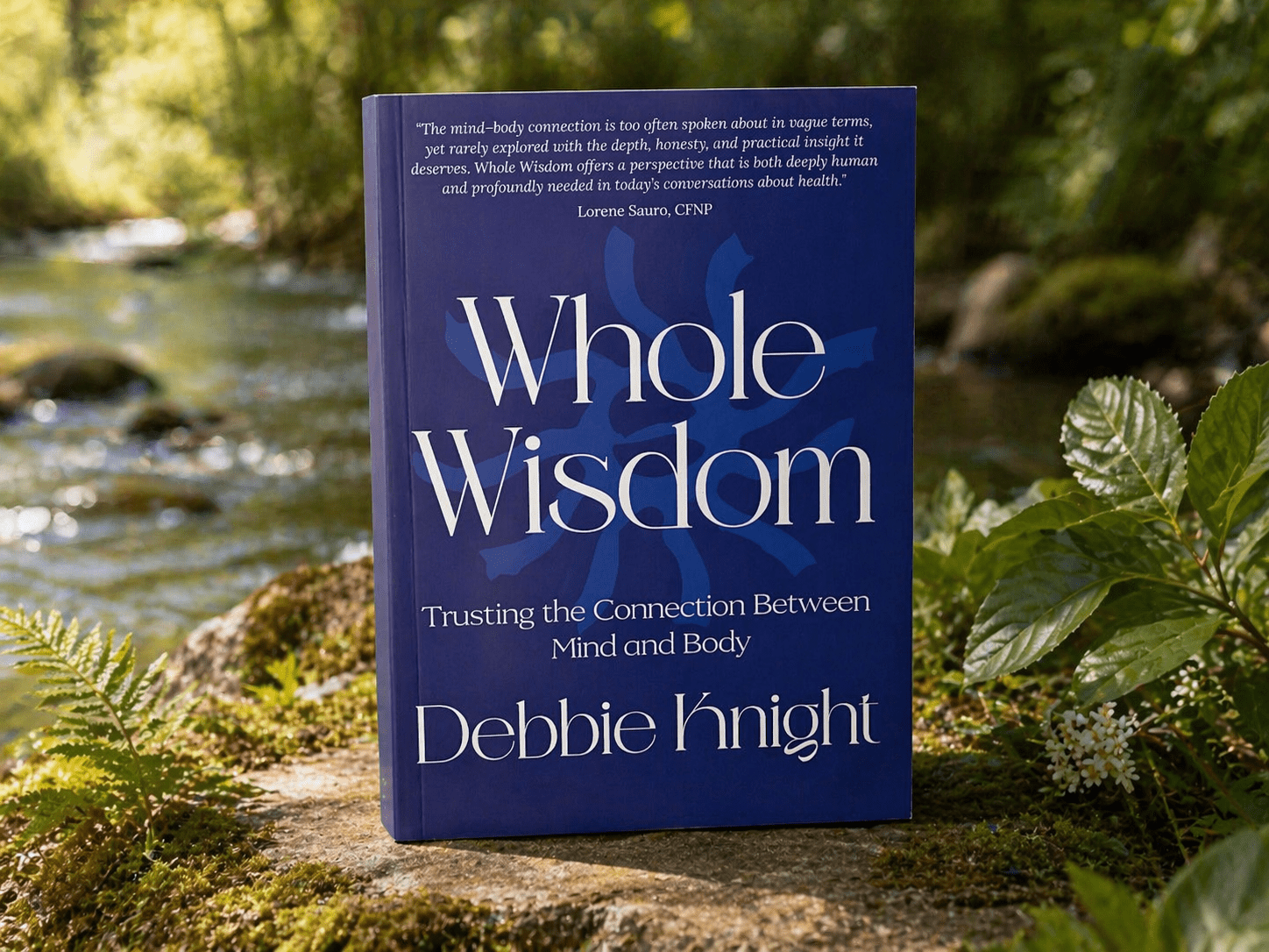 Whole Wisdom book by Debbie Knight on mind-body connection beside a stream