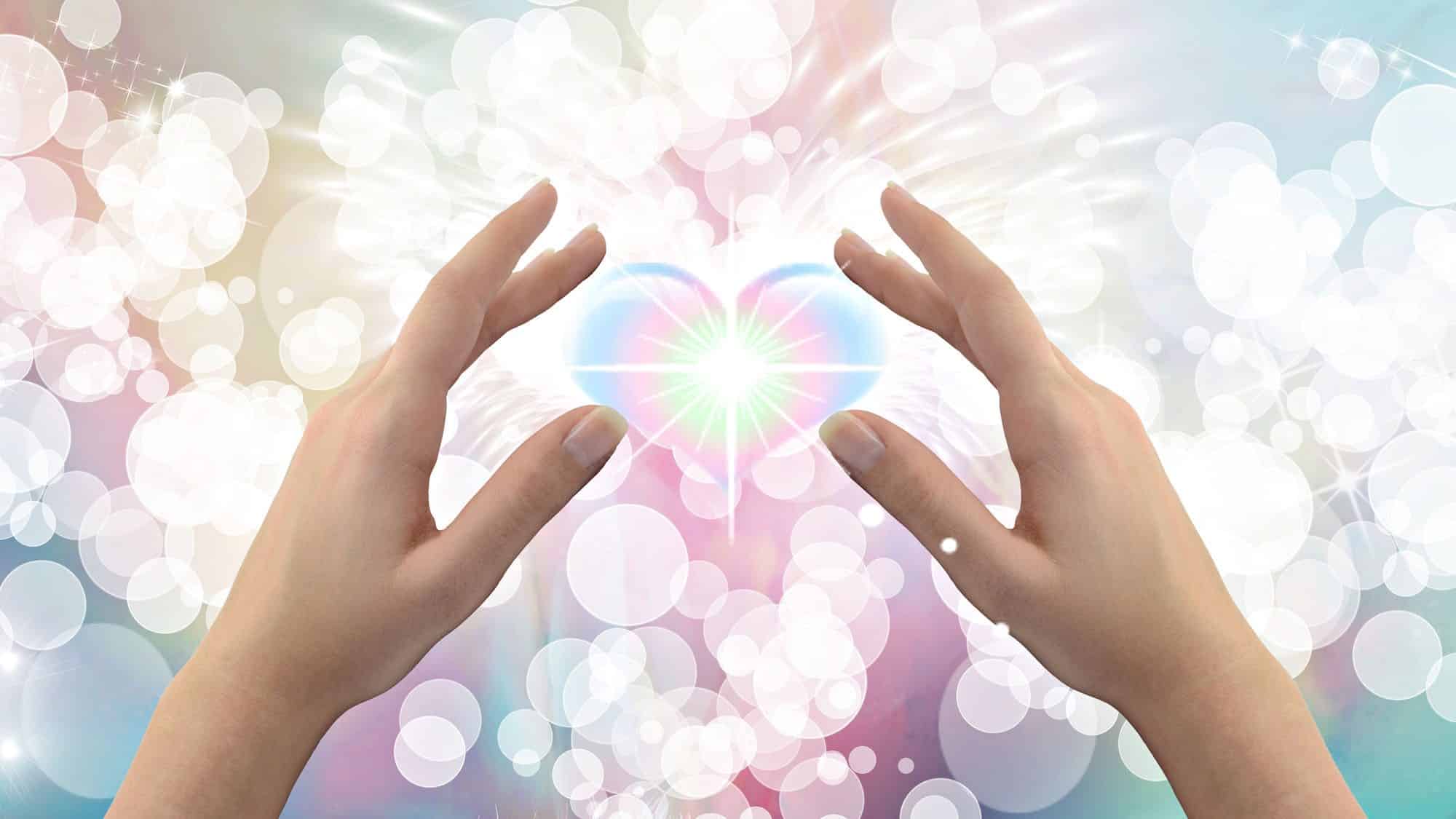 Hands shaping light heart with ethereal bokeh background